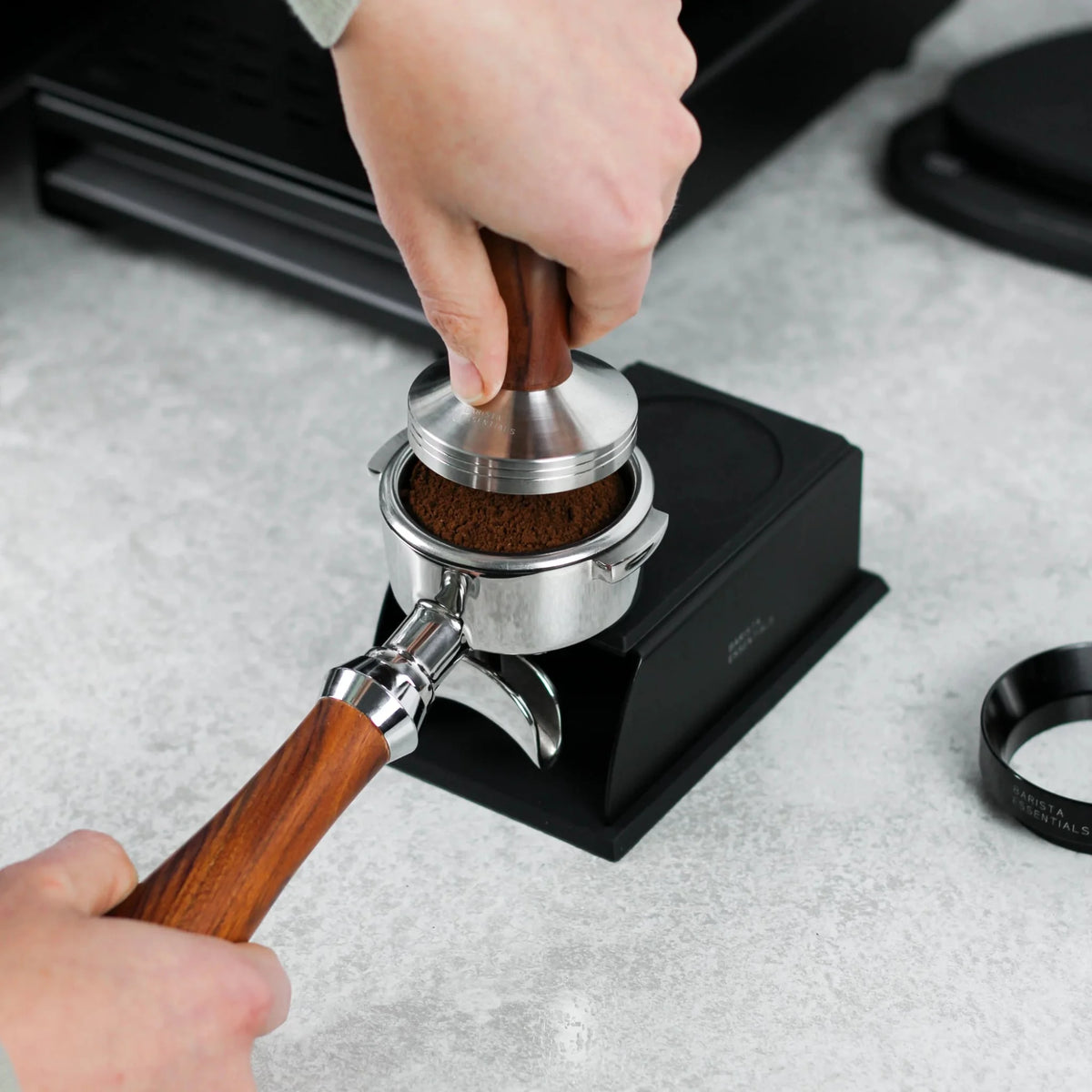 Hand drukt met een tamper koffie aan in een ondersteunde portafilter