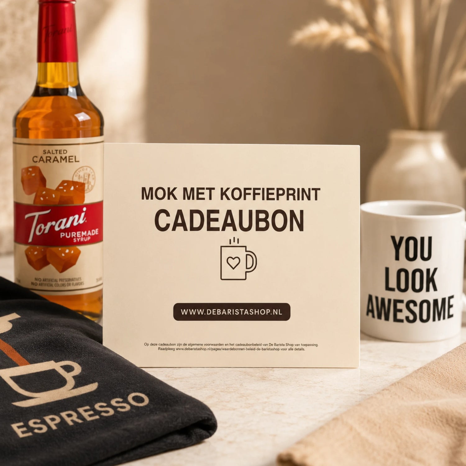Digitale koffie cadeaubon van De Barista Shop als cadeau voor koffieliefhebbers, met mok, koffiesiroop en koffieaccessoires in een warme setting.