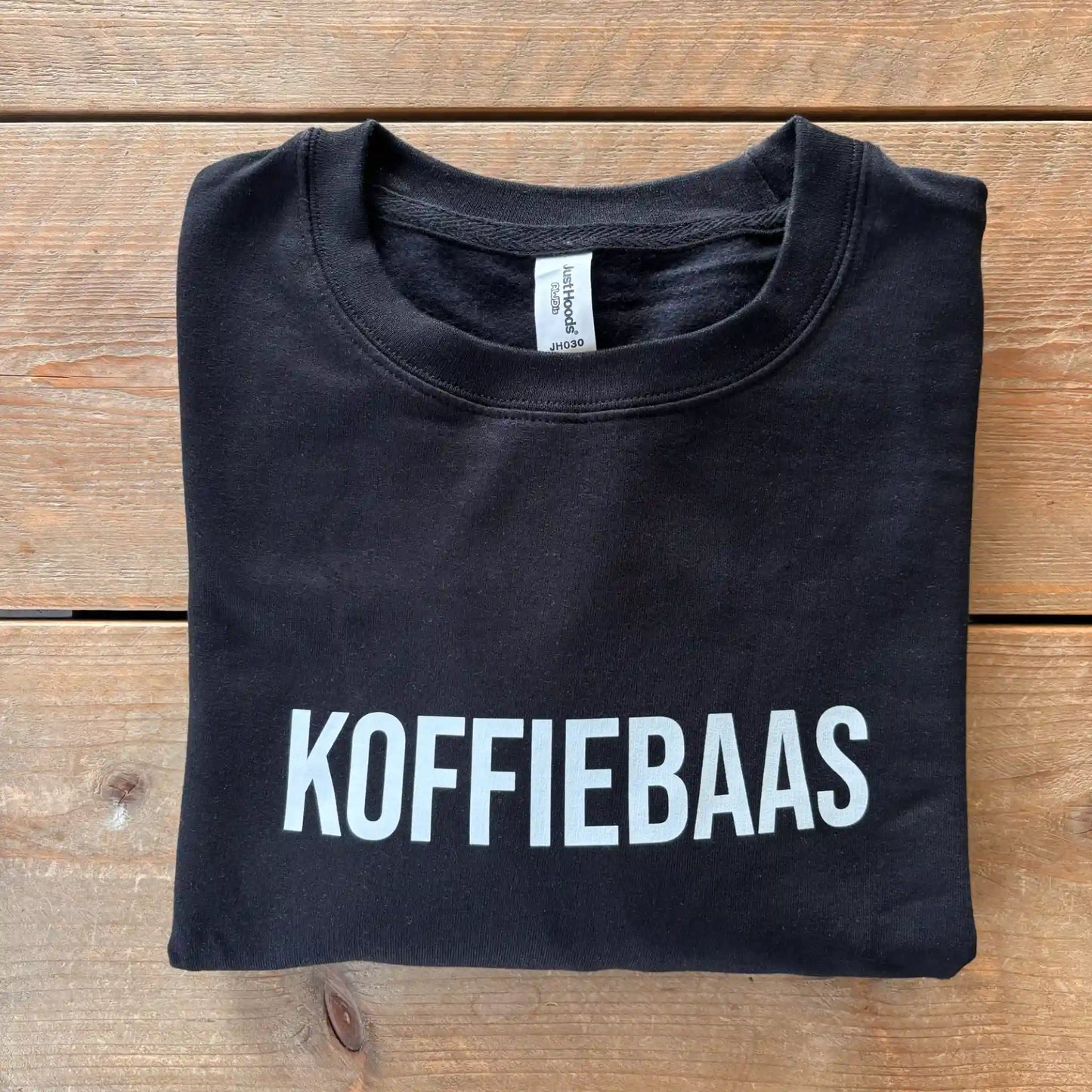 Zwart “KOFFIEBAAS” sweatshirt netjes opgevouwen – perfect koffiecadeau voor barista’s