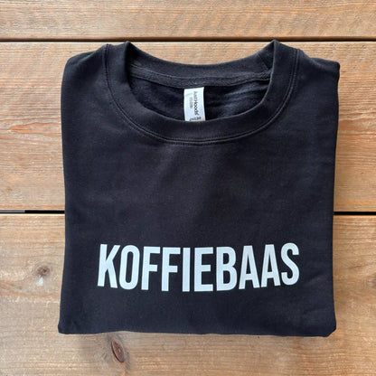 Zwart “KOFFIEBAAS” sweatshirt netjes opgevouwen – perfect koffiecadeau voor barista’s