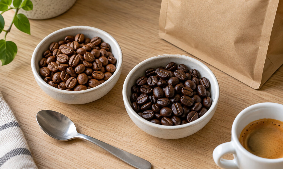 Twee schaaltjes met lichter en donkerder gebrande koffiebonen naast een espresso