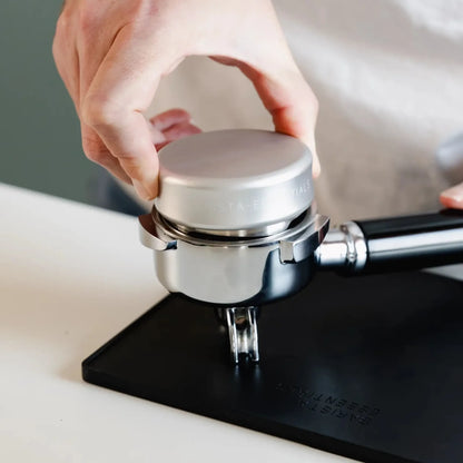 Thuisbarista gebruikt een Barista Essentials koffieverdeler (58 mm) in portafilter op tampingmat