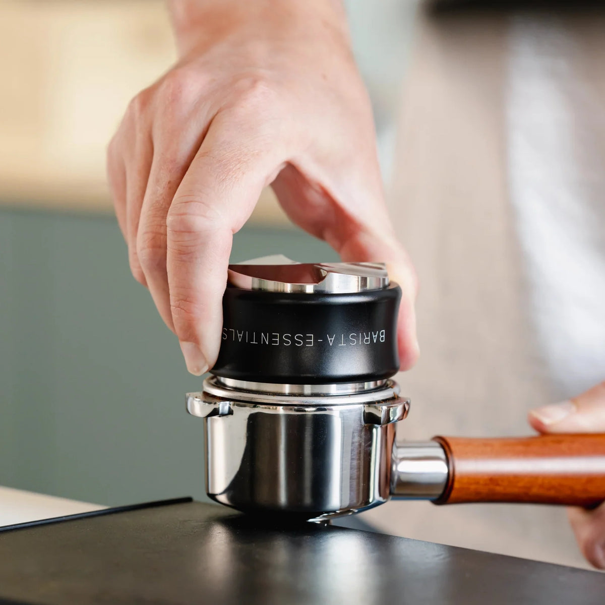 Zwarte koffieverdeler en tamper combinatie tijdens het tampen van koffie in een portafilter