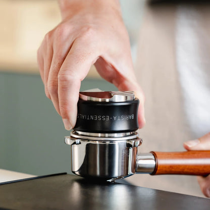 Zwarte koffieverdeler en tamper combinatie tijdens het tampen van koffie in een portafilter