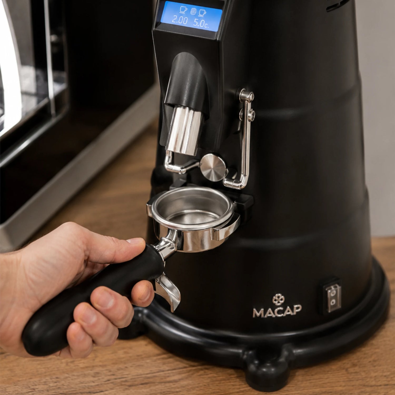 Filterdrager wordt tegen de doseerknop van een Macap MXD koffiemolen gedrukt voor Push and Grind.