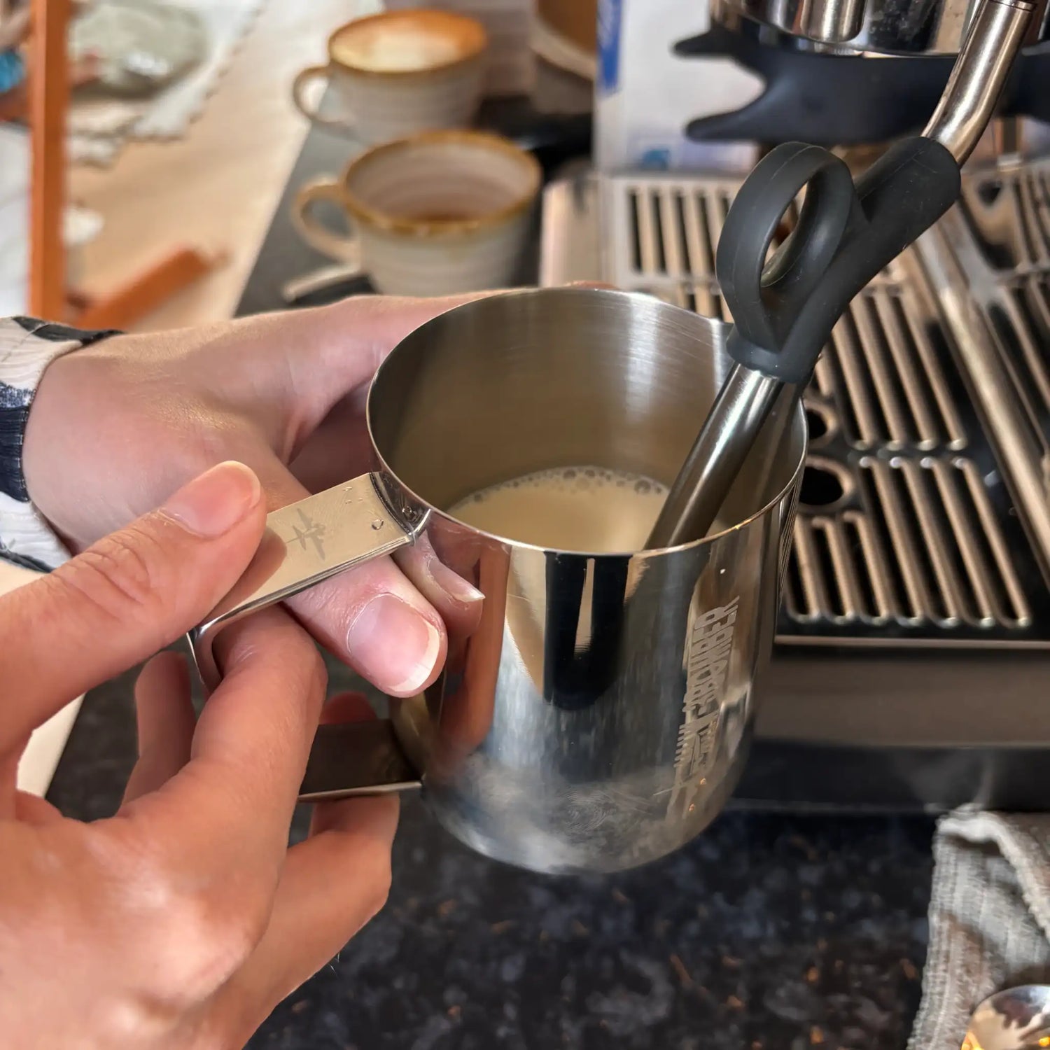 Melk opschuimen met de stoompijp van een Sage Barista Express Impress tijdens een barista-workshop aan huis in Nieuwkoop