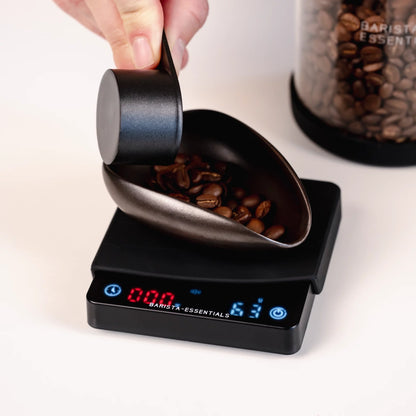 Koffiebonen worden in een doseerschaal op de miniweegschaal gegoten