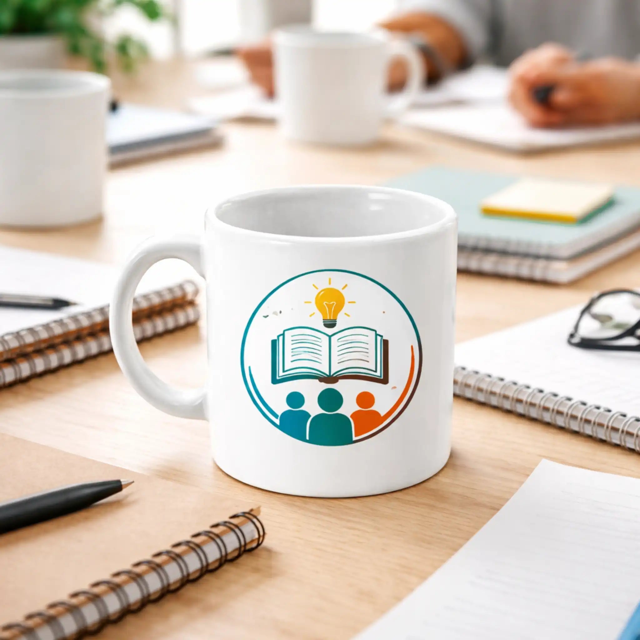 Witte koffiemok met educatief logo (boek en lamp), gebruikt tijdens een training of teamvergadering.