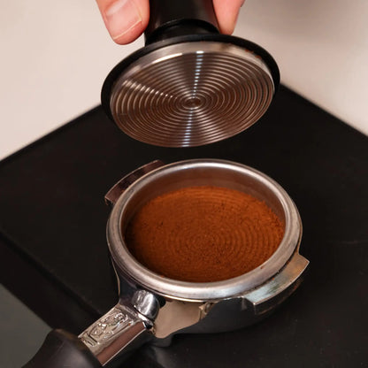 Onderzijde van een gekalibreerde espresso tamper boven een vlak aangedrukte koffiepuck in een portafilter.