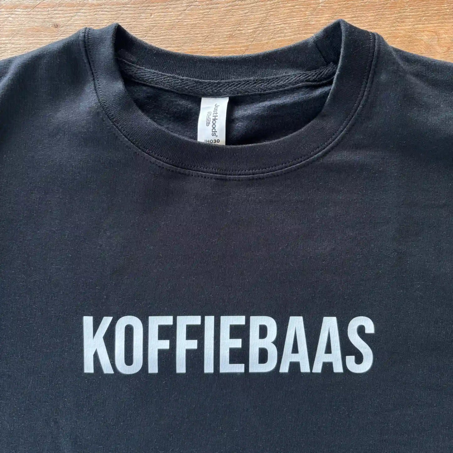 Zwarte KOFFIEBAAS sweater platgelegd met zichtbare witte print