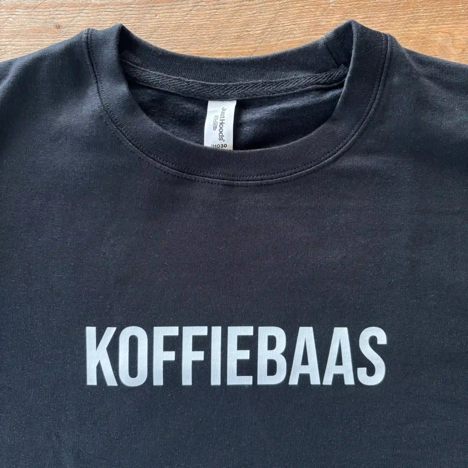 Zwarte KOFFIEBAAS sweater platgelegd met zichtbare witte print