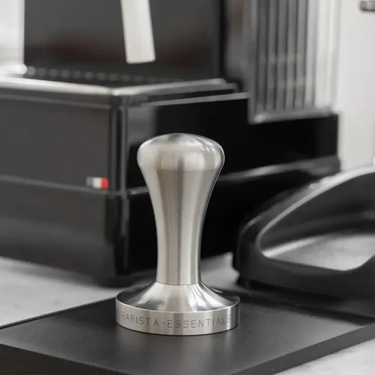 Professionele RVS tamper 58mm naast espressomachine voor meer controle bij espresso zetten