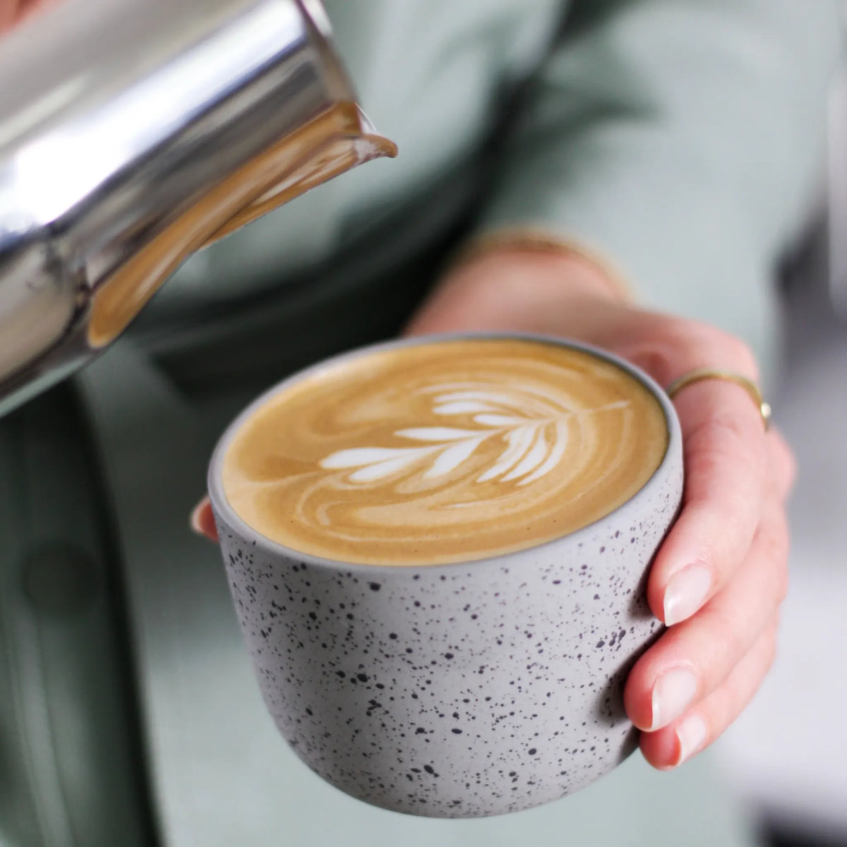 Melk wordt uit een RVS kan in een cappuccinokop geschonken