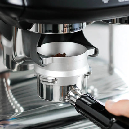 Zilverkleurige 53,3 mm doseerring bevestigd op een portafilter onder de ingebouwde koffiemolen van een Sage Barista Express, tijdens het malen van koffie.