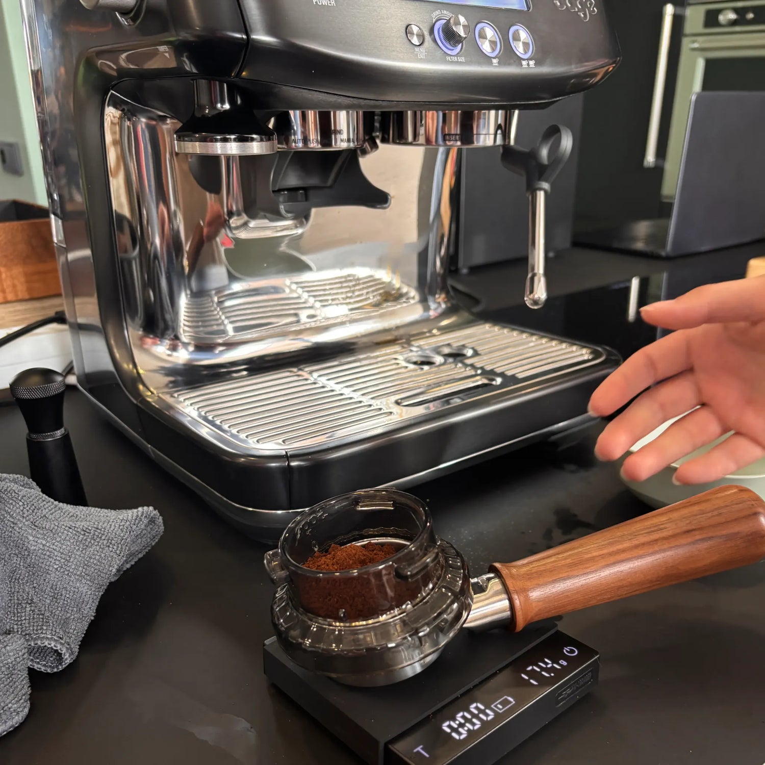 Gemalen koffie wordt in een portafilter gewogen op een koffieweegschaal tijdens een privé barista workshop aan huis met een Sage Barista Pro.