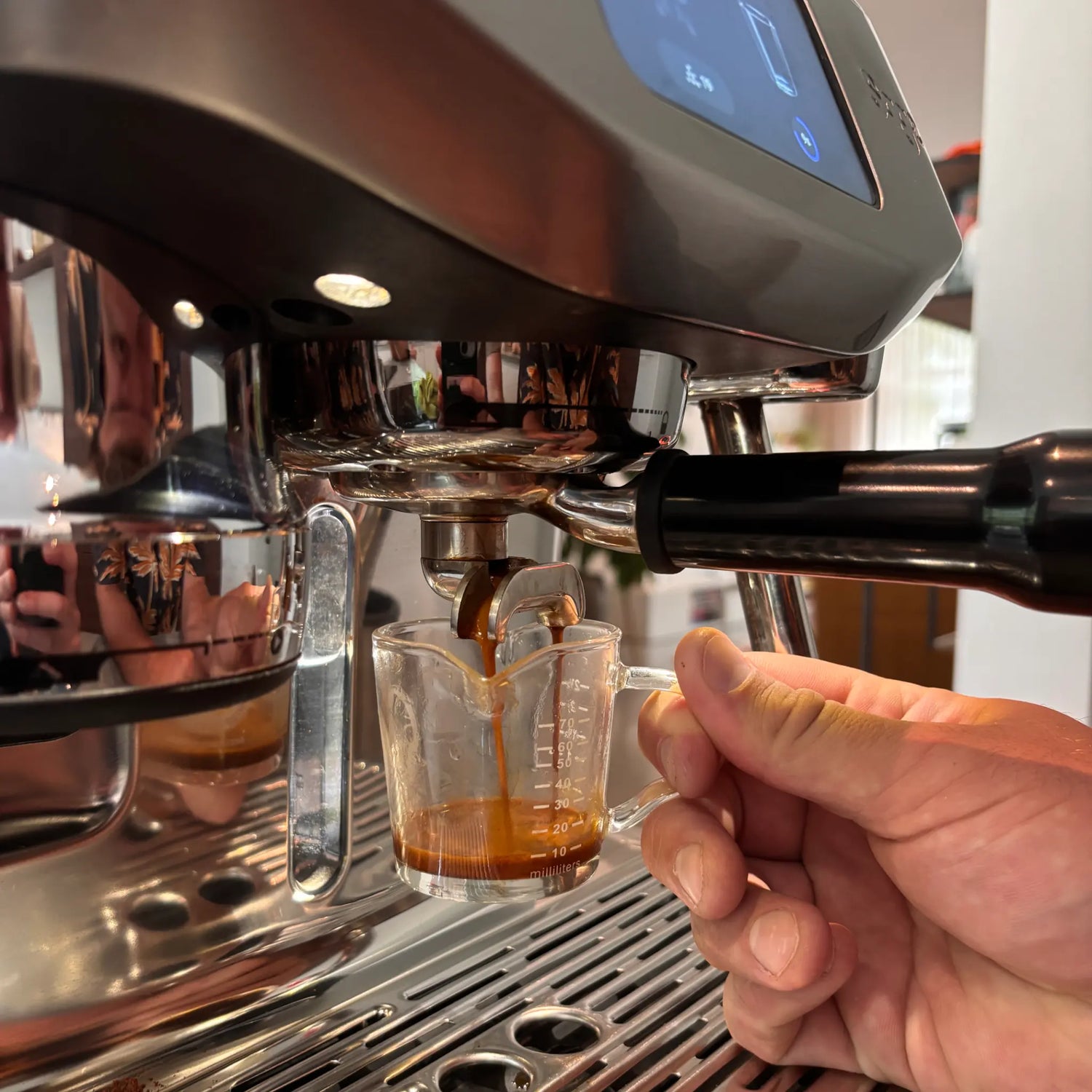 Espresso extractie op een Sage Oracle Jet tijdens een barista workshop aan huis, waarbij espresso in een shotglas wordt gezet op de eigen espressomachine.