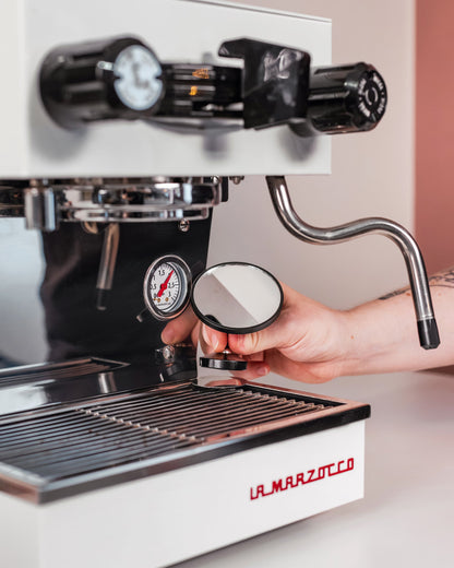 Hand stelt de extractiespiegel op de lekbak van een espressomachine af