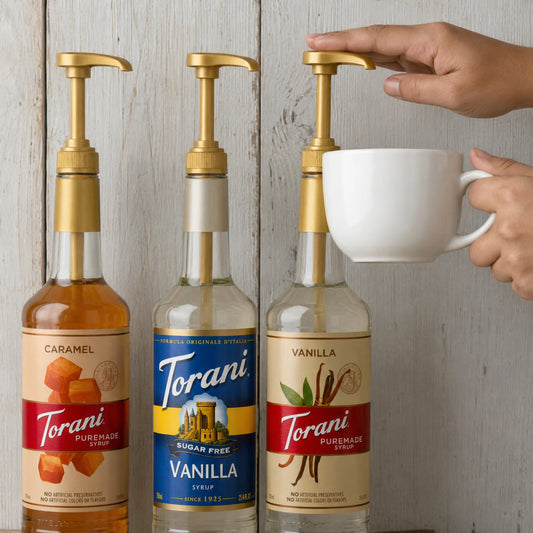 Koffieliefhebber geniet van een warme koffie met Torani PureMade Vanilla vanuit de gouden siroop pomp.