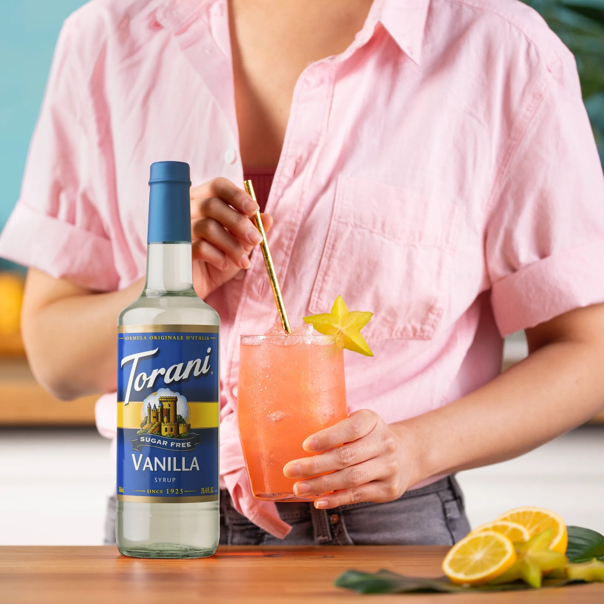 Vrouw serveert een zomerse mocktail met Torani suikervrije vanillesiroop en vers fruit – perfect voor gezonde traktaties zonder suiker