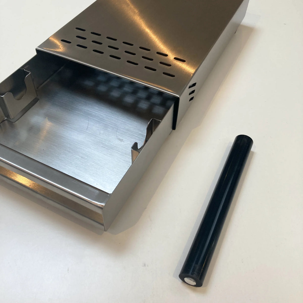 Losse uitklopstang naast een geopende metalen mini-uitkloplade