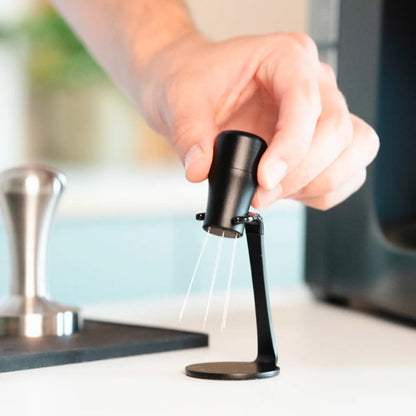 Zwarte WDT-tool met houder wordt na gebruik opgeborgen naast tamper en espressomachine