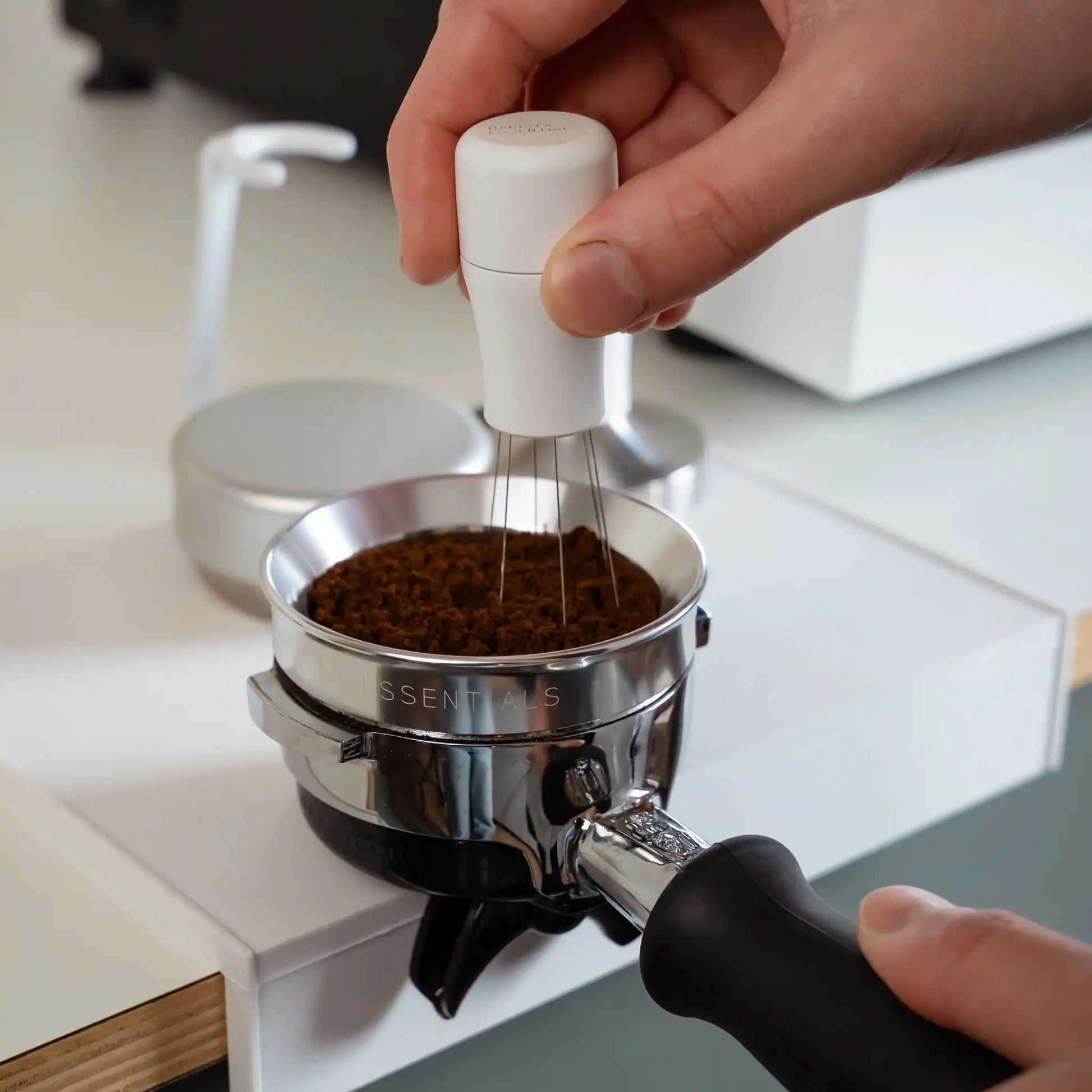 Witte WDT-tool wordt gebruikt om gemalen koffie in de portafilter gelijkmatig te verdelen vóór het tampen