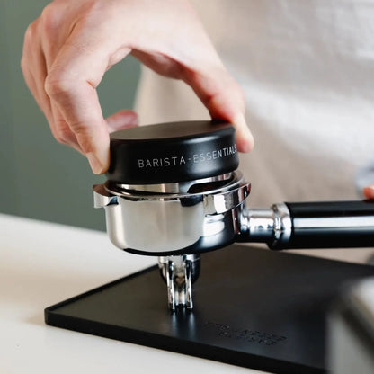 Mat zwarte Barista Essentials koffieverdeler (58 mm) in gebruik door thuisbarista
